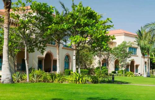 una casa con palmeras en un patio en Al Raha Beach Hotel - Gulf View Room SGL - UAE, en Abu Dabi