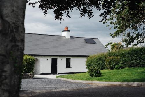 uma casa branca com uma chaminé por cima. em Debbie's Cottage at Tullig House & Farm em Killarney