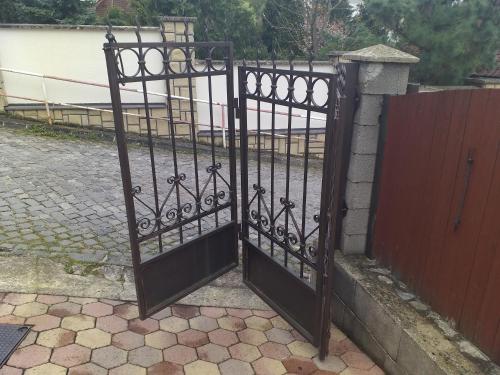 a black iron gate with a red fence at Ubytovanie Clematis in Trenčianske Teplice