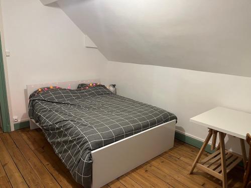 - une petite chambre avec un lit et une couette noire et blanche dans l'établissement Maison de maître dans un village à la campagne, à Origny-en-Thiérache