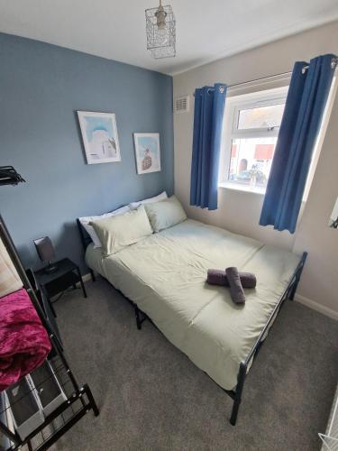 a bedroom with a bed and a window with blue curtains at Beautiful 3BR Home with Garden & Gym in Hull