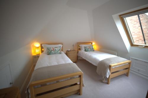 two beds in a small room with a window at The Old Estate Yard, Dumbleton - Near Broadway in Dumbleton