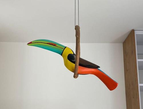 a colorful bird ornament hanging on a wall at Apartment Toucan in Jarocin
