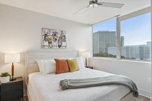 a bedroom with a white bed with a large window at The Eleanor New Orleans in New Orleans