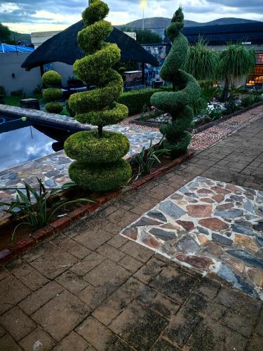 un albero in un giardino vicino a un laghetto di Mukani Guesthouse a Lobatse