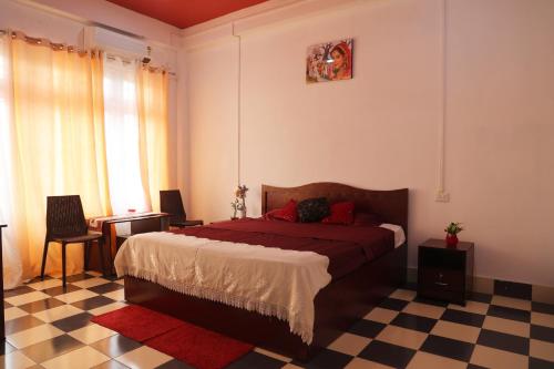 ein Schlafzimmer mit einem Bett und einem karierten Boden in der Unterkunft Cozy Haven in Jorhat