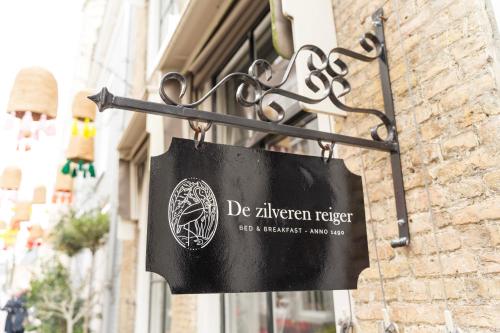 um sinal pendurado no lado de um edifício em B&B De zilveren reiger em Middelburg