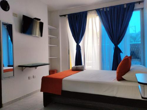 a bedroom with a bed with blue curtains and a window at La Rivera Playa Palomino in Palomino