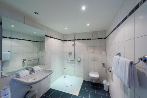 a bathroom with a sink and a shower and a toilet at PANORAMA HOTEL in Neustadt an der Weinstraße in Neustadt an der Weinstraße