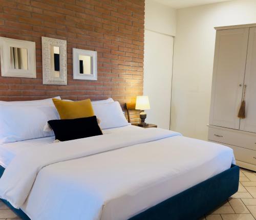 ラストラ・ア・シーニャにあるPodere Gattabigiaのレンガの壁の客室で、白い大型ベッド1台が備わります。