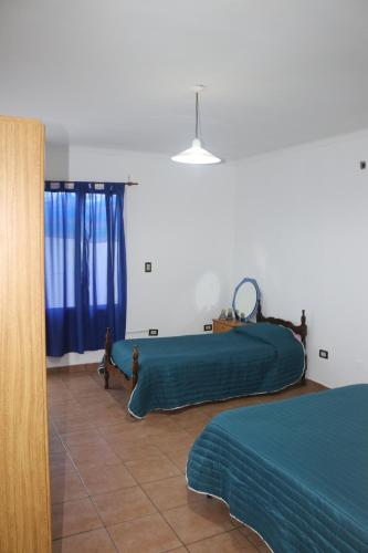 a bedroom with two beds with blue sheets and a person walking through the window at TALCA 3 impuestos incluidos in Godoy Cruz