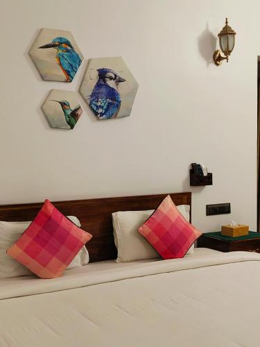 a bedroom with a bed with paintings on the wall at Ananda Holiday Home in Ambalavayal