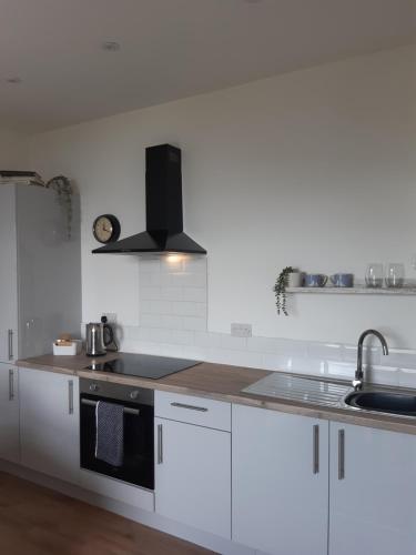 a white kitchen with a sink and a stove at Seasalt Loft in Barmouth
