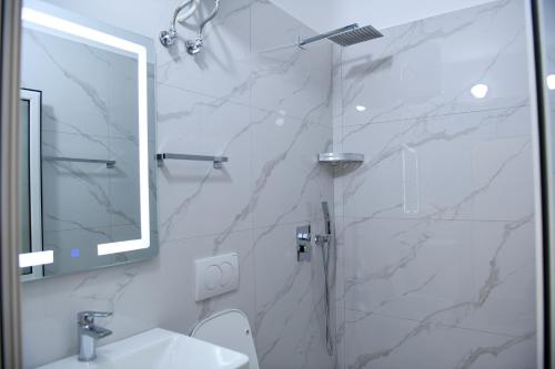 a bathroom with a shower and a sink and a mirror at Guest House Cela City Centre in Berat