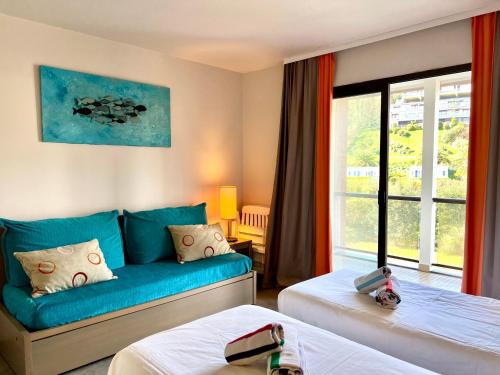 a hotel room with two beds and a couch at DANS LES BRAS DE NEPTUNE - Plage de TRESTRAOU - Piscine - 4 à 5 personnes in Perros-Guirec