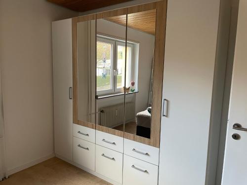 a dressing room with a mirror and white cabinets at FeWo unter der Kirche in Broggingen