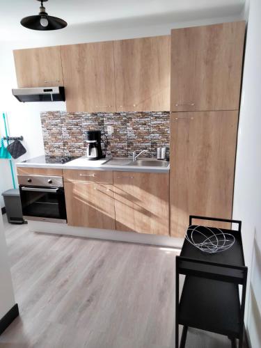 une cuisine avec des armoires en bois, un évier et une cuisinière dans l'établissement L'ECUME, à Pléboulle