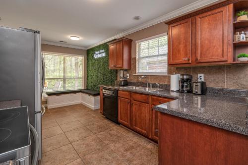 a kitchen with wooden cabinets and a black refrigerator at Wanderlust Willow Trussville Youth Sports Park in Birmingham