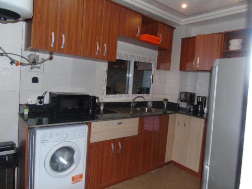 a kitchen with wooden cabinets and a washing machine at Here is our lovely 1-Bed Apartment in Abidjan in Cocody