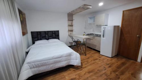 a bedroom with a bed and a kitchen with a refrigerator at Yellow House in Manizales