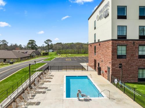 - une piscine en face d'un bâtiment avec des chaises dans l'établissement Cobblestone Hotel & Suites - Cullman, à Cullman