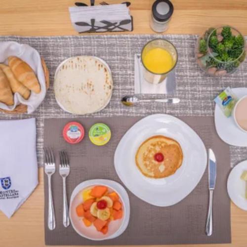 a breakfast table with a plate of food and orange juice at Hotel Montes De La Castellana in Armenia