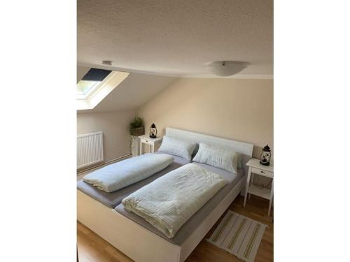 - une chambre mansardée avec un grand lit blanc dans l'établissement Anton - Haus Deichperle, à Dornumersiel