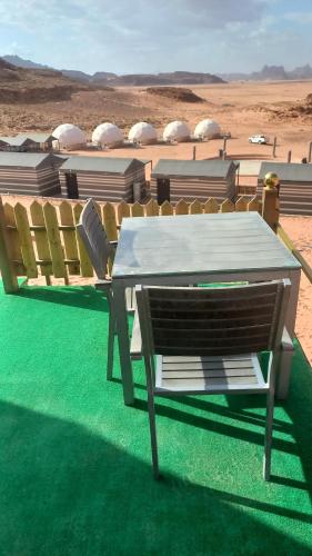 a table and a chair sitting on the grass at Sultan Luxury Camp in Wadi Rum