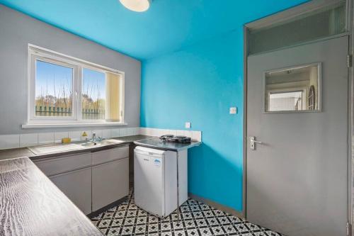 a blue kitchen with a sink and a window at Cosy Retreat: Near Attractions & Comfortable! in Birmingham