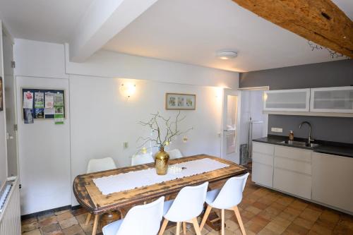 a kitchen with a table and white chairs at Anno 1877 appartement met tuin in Slenaken
