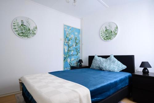 ein Schlafzimmer mit einem blauen Bett und zwei Platten an der Wand in der Unterkunft Anno 1877 appartement met tuin in Slenaken
