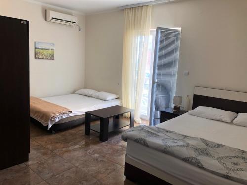 a bedroom with two beds and a table and a window at Vila Bronhi in Sutomore