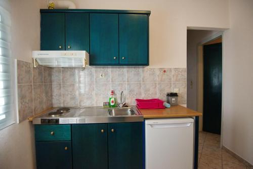 a kitchen with green cabinets and a sink at Studios Nelli Alonissos in Patitiri