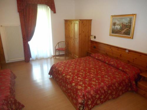 a bedroom with a red bed and a window at Garnì Lago Alpino in Molveno