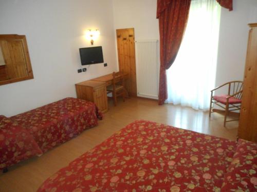 a hotel room with two beds and a television at Garnì Lago Alpino in Molveno