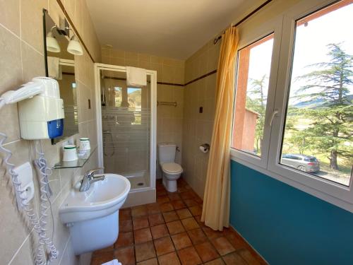 a bathroom with a sink and a toilet and a window at Auberge la Table du Curé in Cucugnan