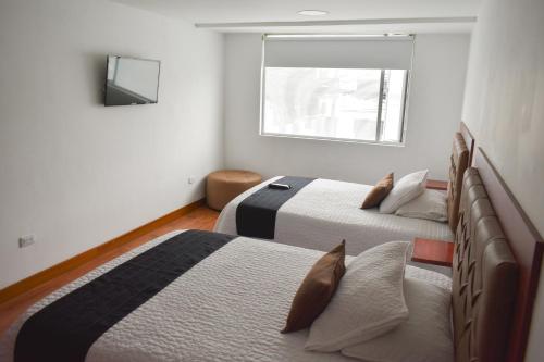 a bedroom with two beds and a window at Hotel Casa Botero 201 in Bogotá
