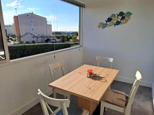- une table et des chaises en bois dans une chambre avec fenêtre dans l'établissement Les terrasses de la plage 255, T3 bien équipé, wifi, parking, au Cap d'Agde