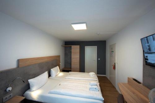 a bedroom with two beds and a tv on the wall at PANORAMA HOTEL in Neustadt an der Weinstraße in Neustadt an der Weinstraße