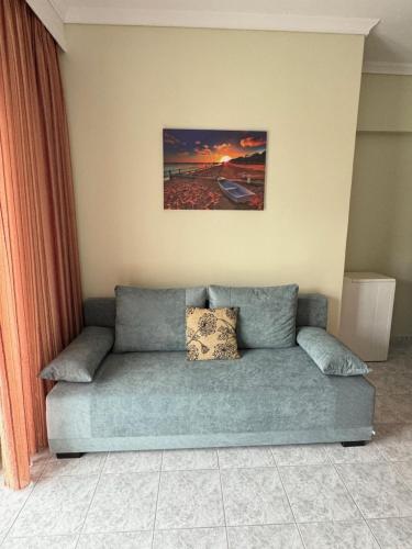 a couch in a living room with a painting on the wall at Calypso Seaside Apartment in Paleo Tsifliki