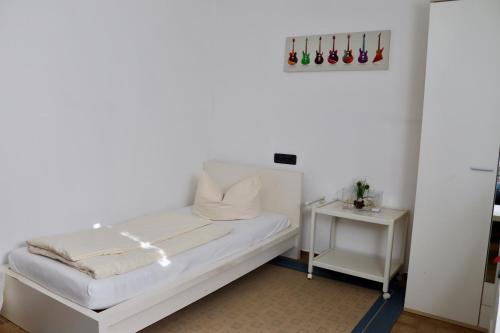 a white room with a bed and a side table at Drei Linden Siedlung in Wolfenbüttel