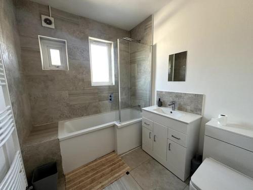 a bathroom with a sink and a tub and a sink and a toilet at Spacious Holiday Home Near Tube Station - By Starlet Stays in London