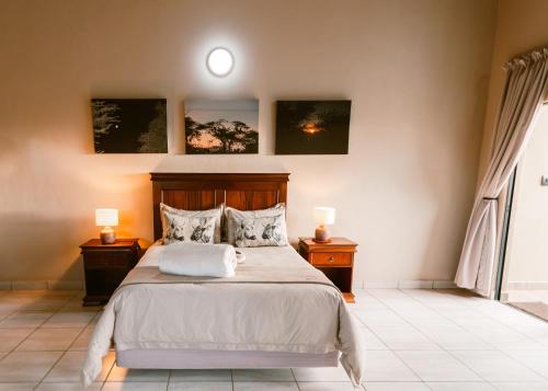 a bedroom with a bed with two night stands and two lamps at Umkhaya lodge in Mkuze