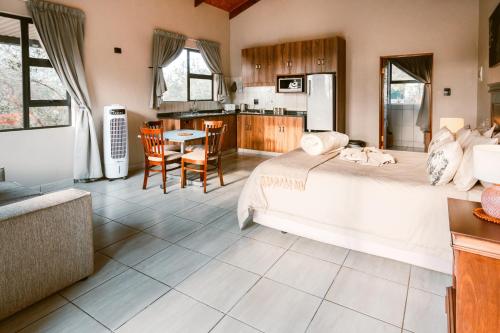a bedroom with a large bed and a kitchen at Umkhaya lodge in Mkuze