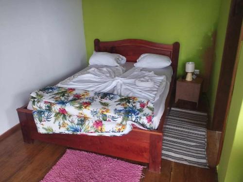 a small bed in a room with a green wall at Pousada Bem Posta in São Tomé