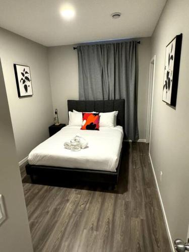 a bedroom with a bed with white sheets and a window at Private Luxury Suite Near West Edmonton Mall in Edmonton
