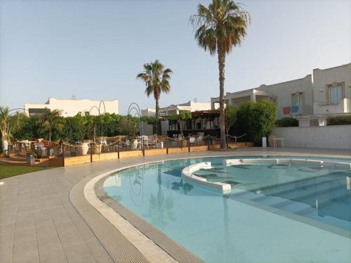a large swimming pool with palm trees and buildings at Mary Holiday Home in Ispica