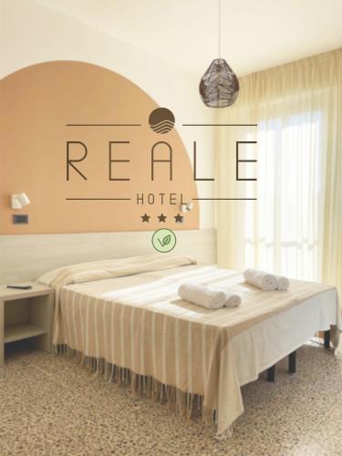 una camera d'albergo con un letto e asciugamani di Hotel Reale a Rimini