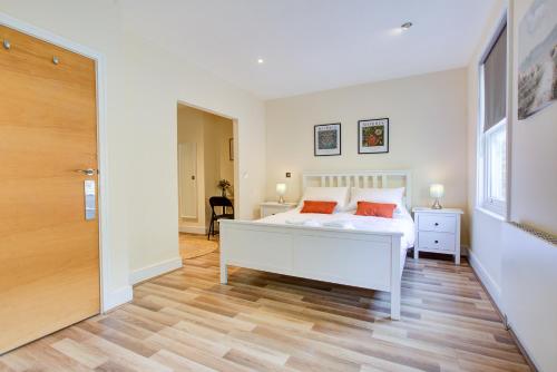 - une chambre avec un lit blanc et du parquet dans l'établissement Stunning 4 Bedroom House, à Londres