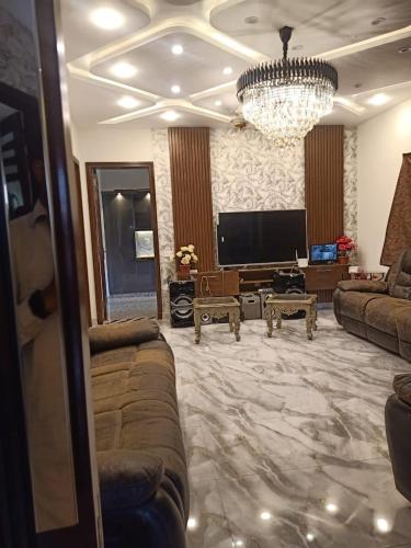 een woonkamer met een bank en een kroonluchter bij One bedroom flat available for month in al qasmiyah in Sharjah